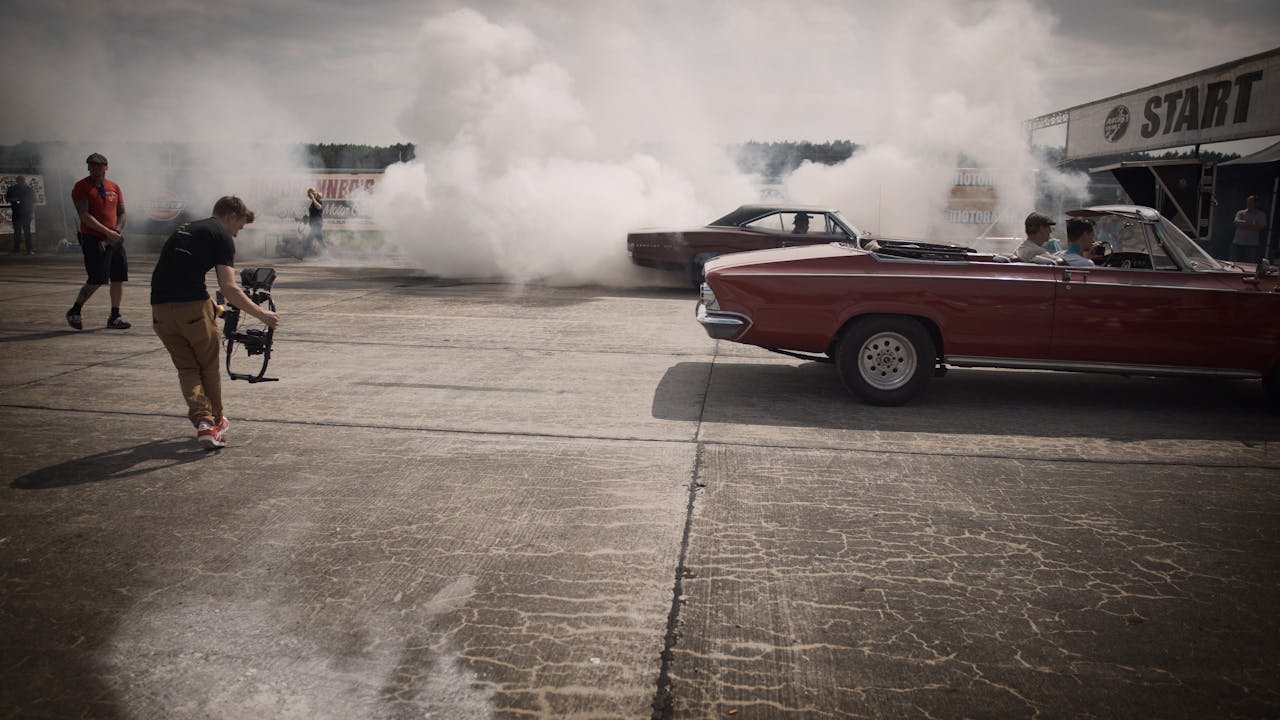 Crafting Captivating Headlines: Your awesome post title goes here A dynamic scene of classic cars and filmmakers capturing a smoky drag race event.