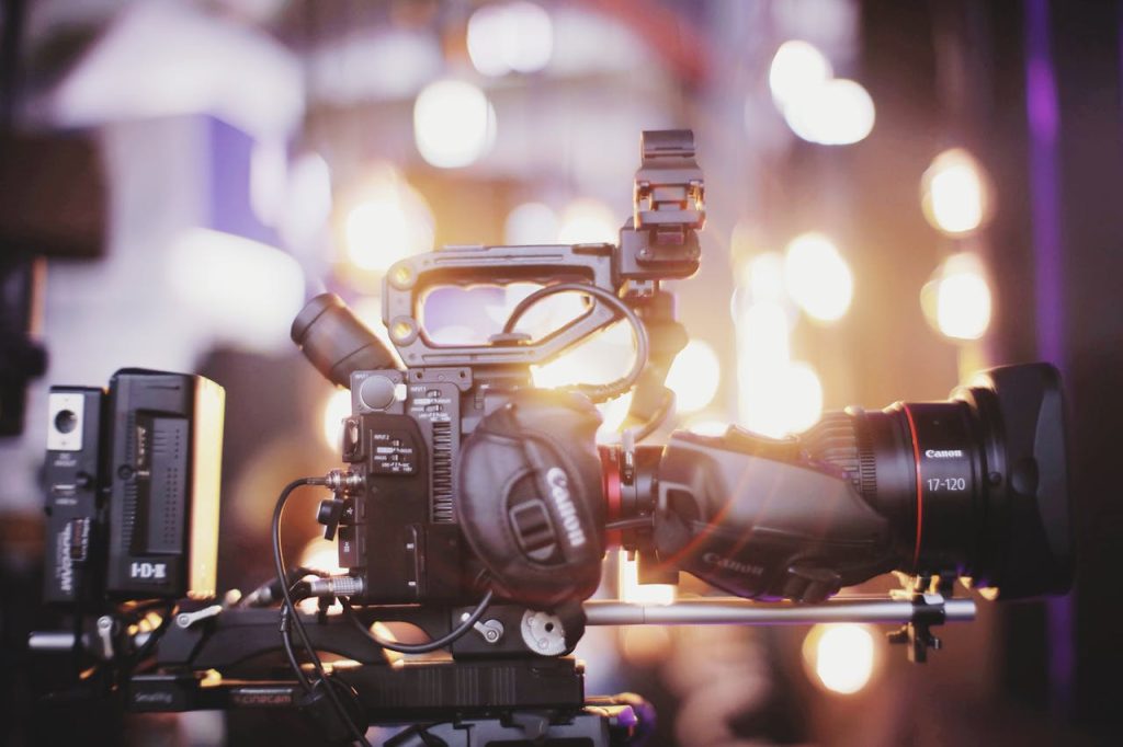 pexels photo 2865263 1 Close-up of professional video camera setup for studio filming with blurred lights in the background.